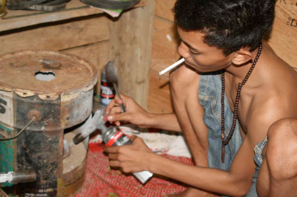 A child worker burns mercury amalgam while smoking. Inhaling mercury is one of the most direct and dangerous ways of taking it into the human body. (Omar Pidani and Fitrilailah Mokui) A child worker in a squatting position, burning mercury amalgam while smoking a cigarette.